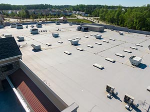 Single-Ply-Roofers-Butte-MT-Montana-2 | Schrock Roofing Flat white commercial roof with multiple skylights and HVAC units, surrounded by trees in the distance.